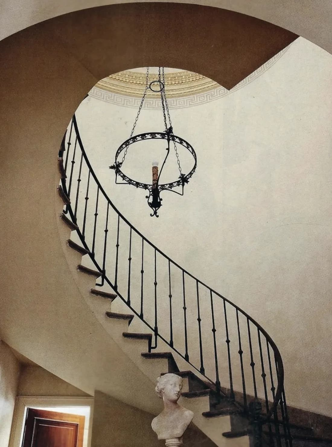 AD100 studio — curved stair under an iron chandelier