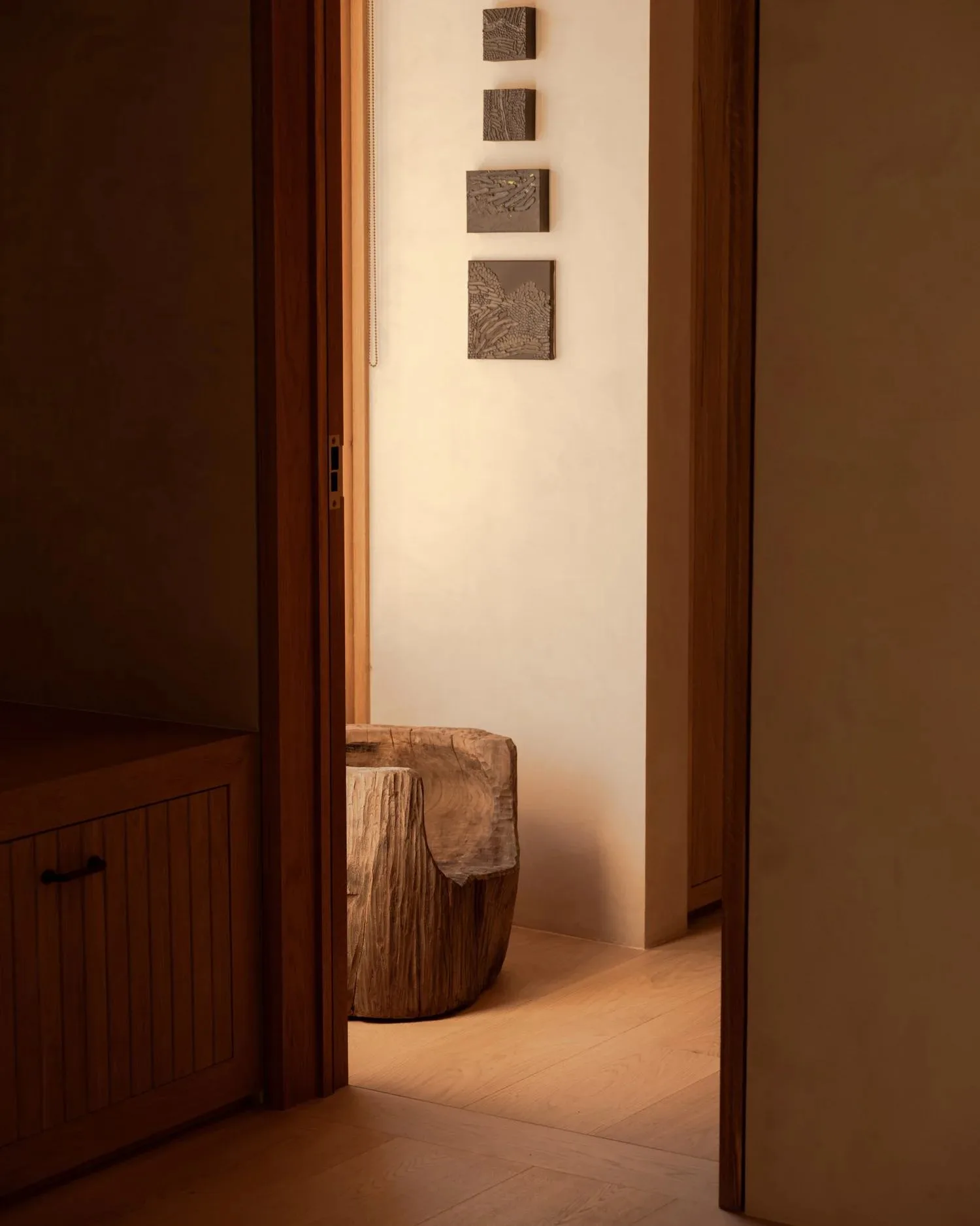 Warm wood-panelled hallway with carved stool and wall reliefs