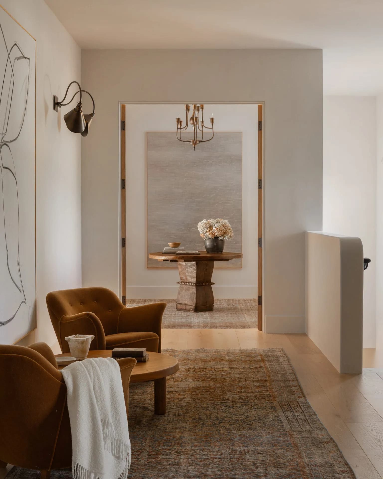 Sunlit sitting room with camel armchairs and a round oak table
